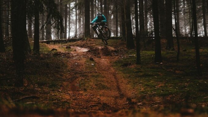 Terrengsyklist hopper over en ujevn sti i tett skog
